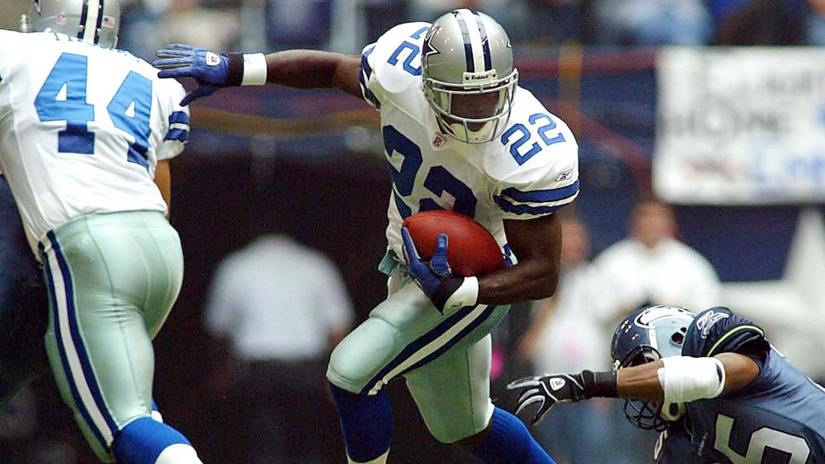 IRVING, TX - OCTOBER 27: Emmitt Smith (C) of the Dallas Cowboys runs behind the block of fullback Robert Thomas (L) as Reggie Tongue (R) of the Seattle Seahawks tries to make the tackle in first half action at Texas Stadium in Irving, Texas, 27 October, 2002. Smith eclipsed the mark owned by Walter Payton of the Chicago Bears of 16,726 yards. (Photo credit should read PAUL K. BUCK/AFP via Getty Images)