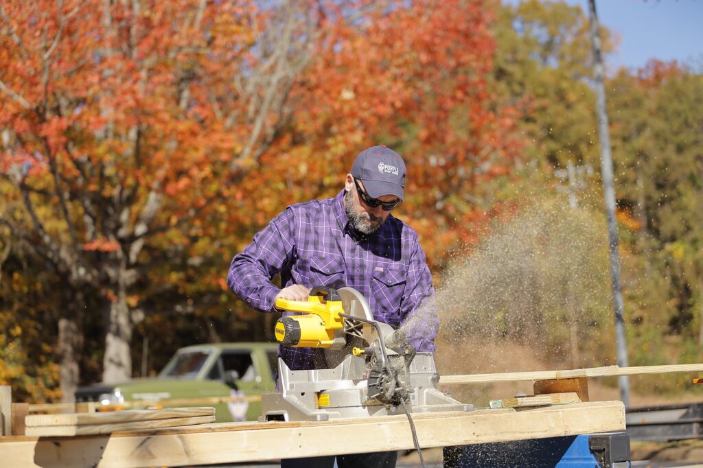 Volunteer cuts wood for ramp construction